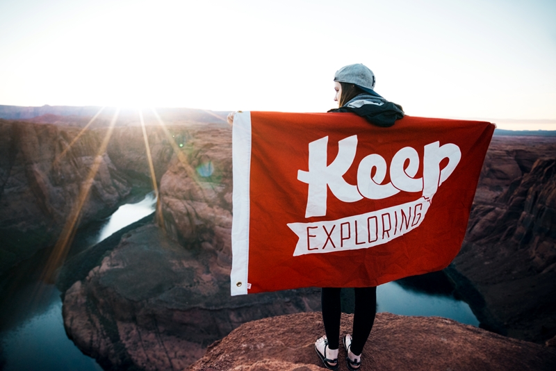Dziewczyna z flagą Keep Exploring na szczycie Fot. Justin Luebke/Unsplash