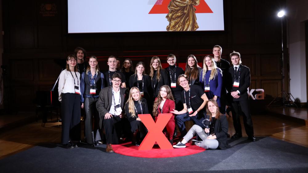 Zdjęcie grupowe uczestników Konferencji TEDxPolitechnika Gdańska 2025 na ściance zdjęciowej.