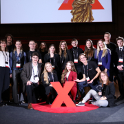 Zdjęcie grupowe uczestników Konferencji TEDxPolitechnika Gdańska 2025 na tle bilboardu.