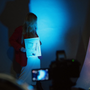 Zdjęcie kobiety trzymającej zdjęcie prac warsztatowych dzieci w ciemnym oświetleniu.