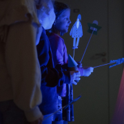 Zdjęcie dzieci w fioletowym świetle trzymających zrobione pacynki.