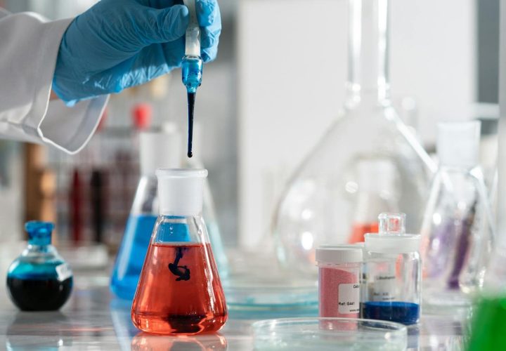 Scientist conducting a laboratory experiment with colorful chemical solutions and scientific glassware.