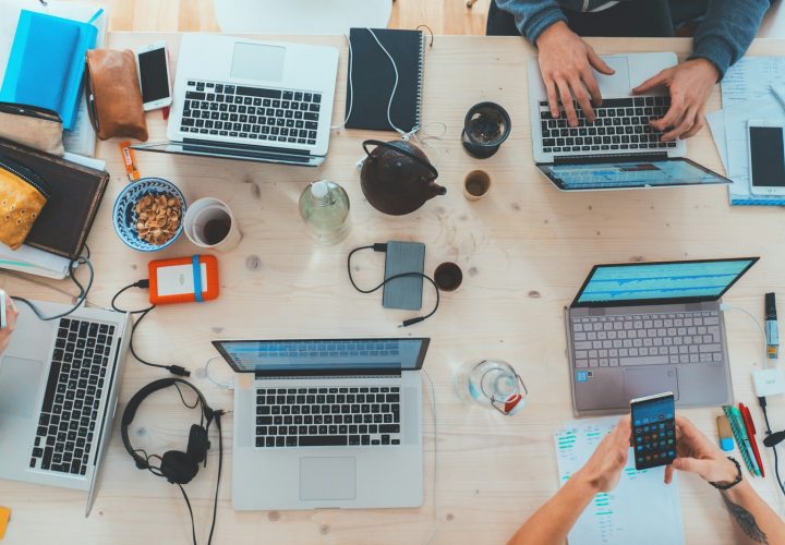 people sitting down near table with assorted laptop computers
